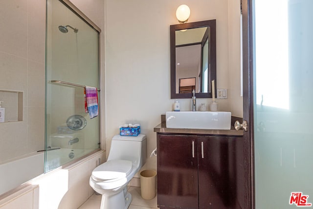 full bathroom featuring tile patterned flooring, vanity, bath / shower combo with glass door, and toilet