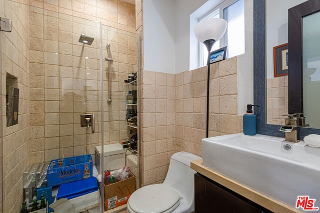 bathroom with vanity, toilet, tile walls, and a tile shower