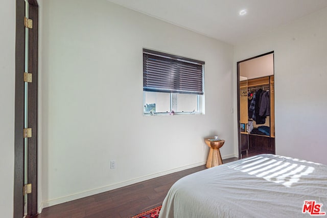 bedroom with dark wood-type flooring, a walk in closet, and a closet