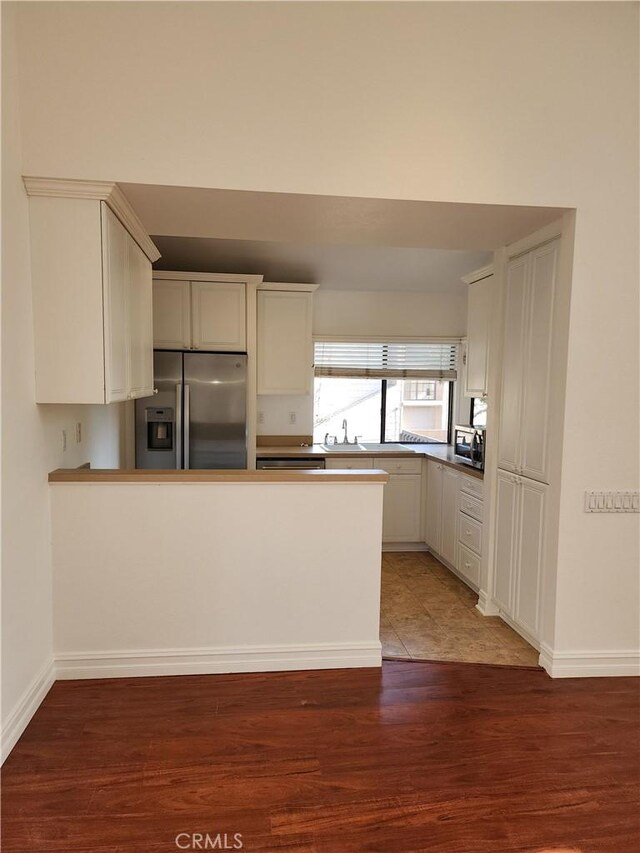 kitchen with sink, appliances with stainless steel finishes, dark hardwood / wood-style flooring, kitchen peninsula, and white cabinets