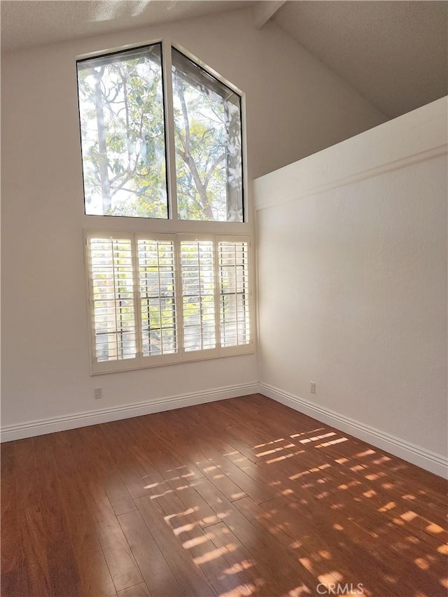 unfurnished room featuring dark wood-type flooring and high vaulted ceiling