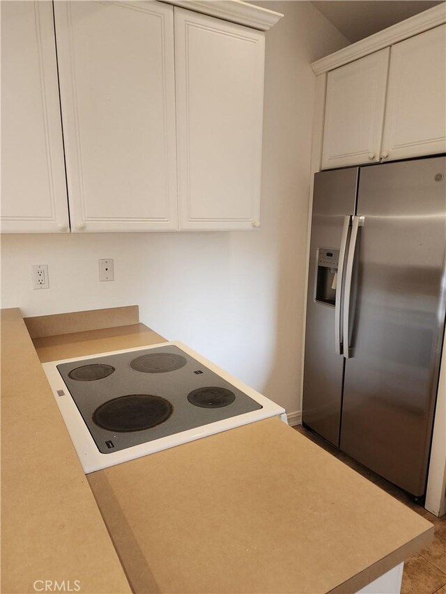 kitchen with stainless steel fridge with ice dispenser, white electric cooktop, and white cabinets