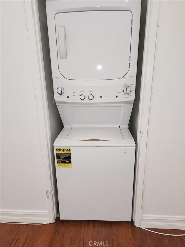 laundry room with stacked washing maching and dryer and dark wood-type flooring