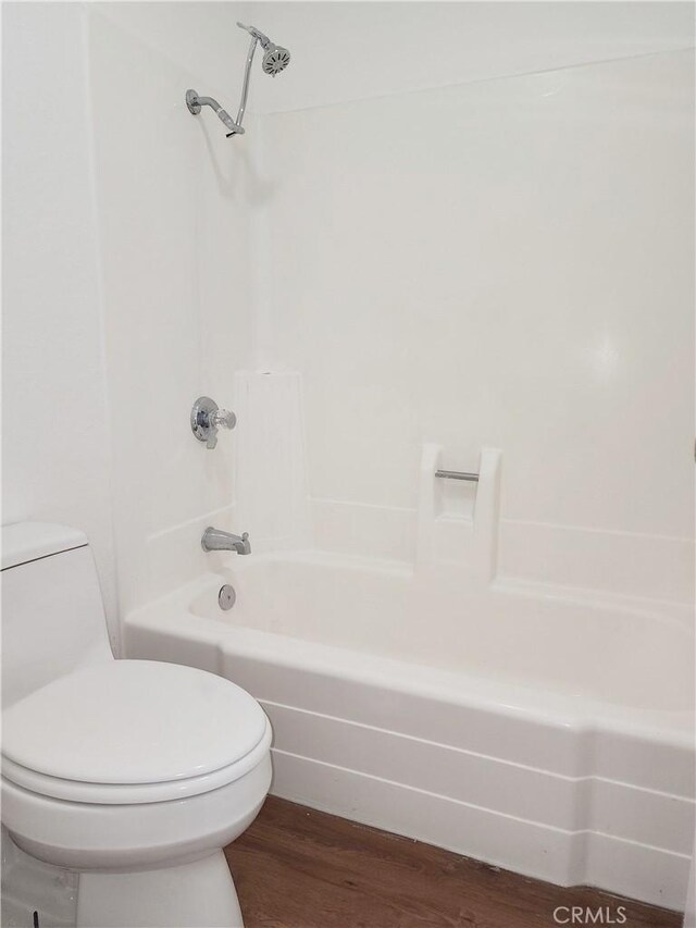 bathroom with hardwood / wood-style floors, shower / washtub combination, and toilet