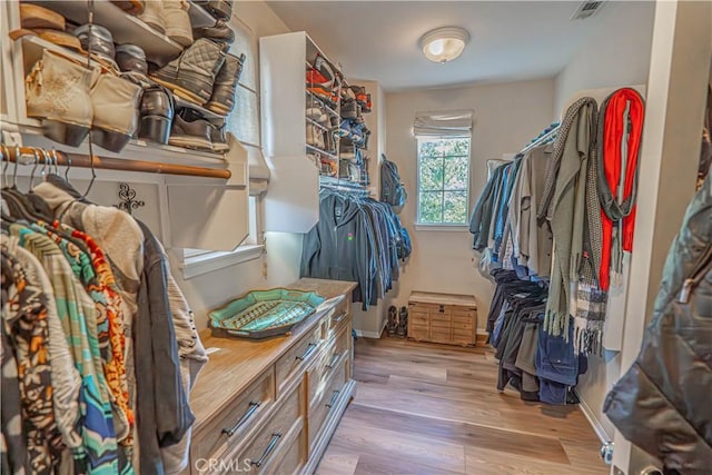 walk in closet with light hardwood / wood-style flooring