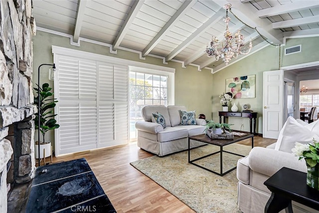 living room with a healthy amount of sunlight, wood-type flooring, vaulted ceiling with beams, and an inviting chandelier