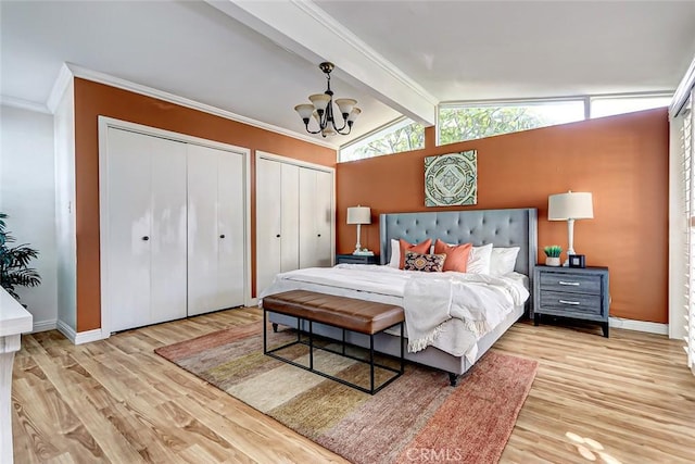 bedroom featuring vaulted ceiling with beams, crown molding, a chandelier, light hardwood / wood-style flooring, and two closets