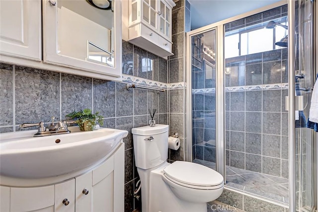 bathroom with tile walls, backsplash, vanity, an enclosed shower, and toilet