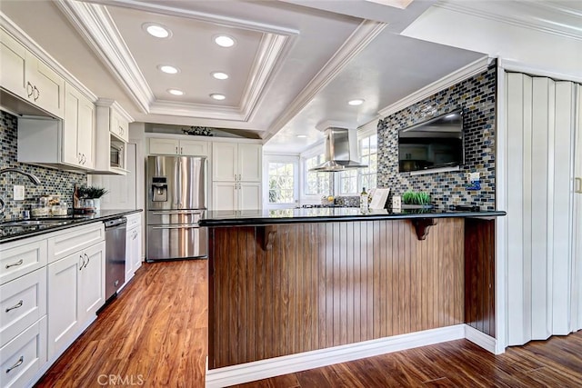 kitchen featuring white cabinetry, appliances with stainless steel finishes, a breakfast bar area, and range hood