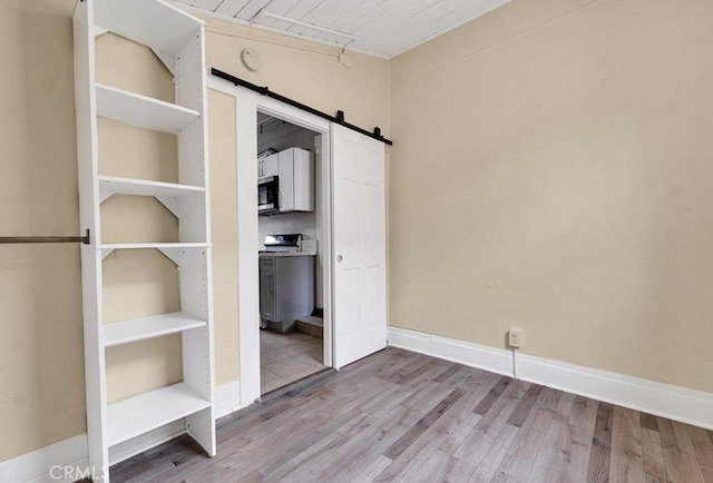 unfurnished bedroom with hardwood / wood-style flooring and a barn door