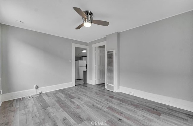 empty room with ceiling fan and light hardwood / wood-style flooring