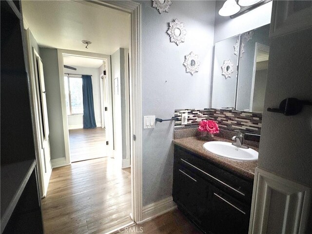 bathroom featuring hardwood / wood-style flooring, vanity, and decorative backsplash