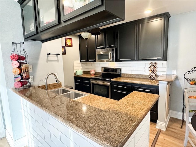 kitchen featuring stainless steel appliances, sink, backsplash, and kitchen peninsula