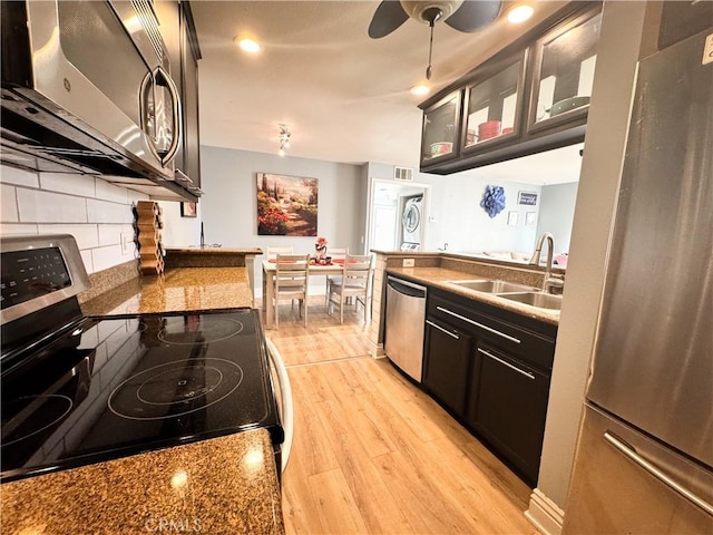 kitchen featuring appliances with stainless steel finishes, tasteful backsplash, sink, ceiling fan, and light hardwood / wood-style floors