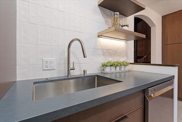 kitchen featuring dishwasher, sink, tile walls, and backsplash