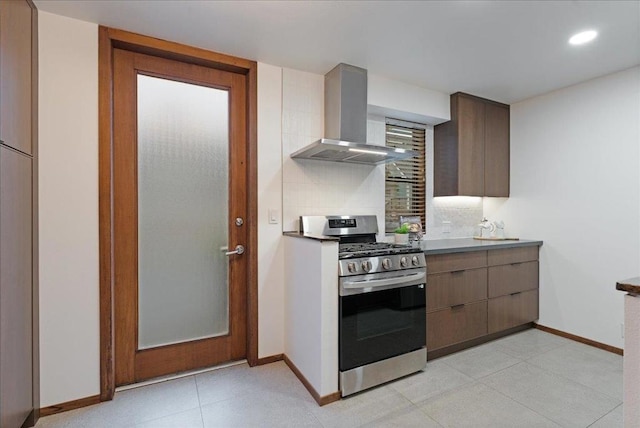 kitchen with stainless steel gas range, light tile patterned floors, decorative backsplash, and wall chimney range hood