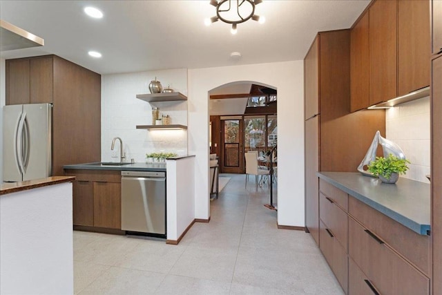 kitchen with light tile patterned flooring, appliances with stainless steel finishes, sink, and decorative backsplash