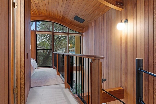 corridor featuring lofted ceiling, wood ceiling, and wood walls