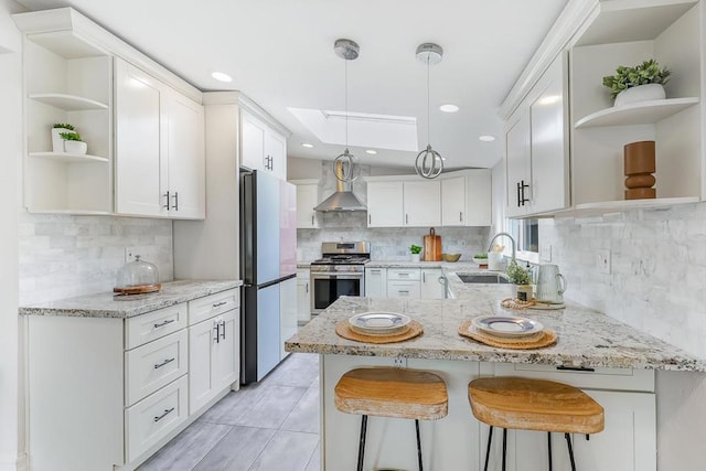 kitchen with sink, refrigerator, white cabinetry, stainless steel range, and kitchen peninsula