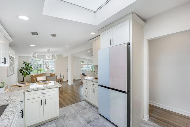 kitchen featuring white cabinetry, refrigerator, light hardwood / wood-style floors, and light stone countertops