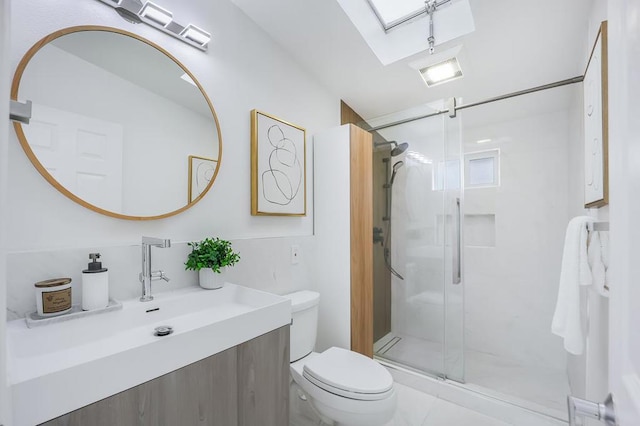 bathroom featuring vanity, toilet, a skylight, and a shower with door