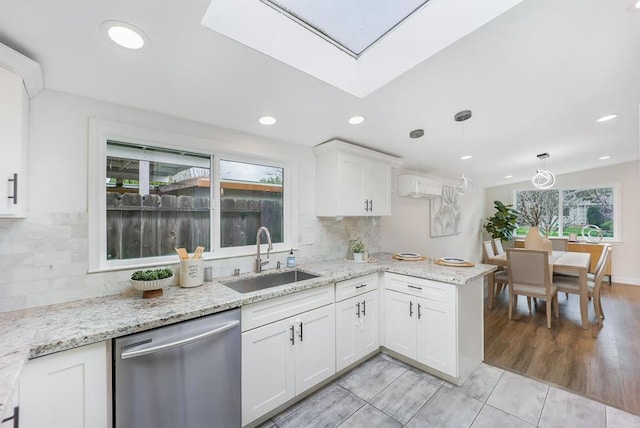 kitchen featuring white cabinetry, dishwasher, hanging light fixtures, and sink