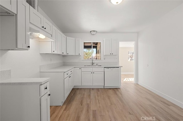 kitchen featuring white dishwasher, sink, light hardwood / wood-style flooring, and white cabinets