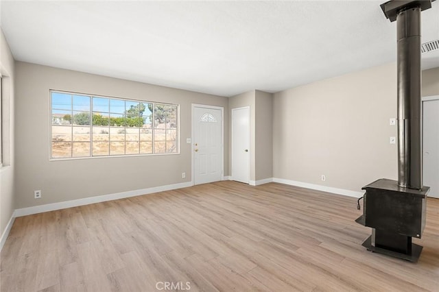 unfurnished living room featuring light hardwood / wood-style flooring and a wood stove