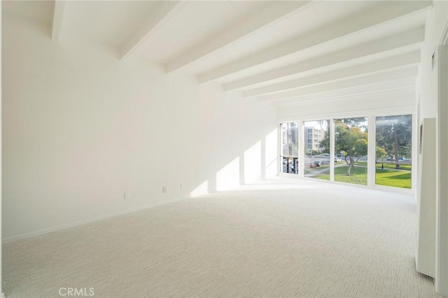 carpeted empty room featuring beamed ceiling