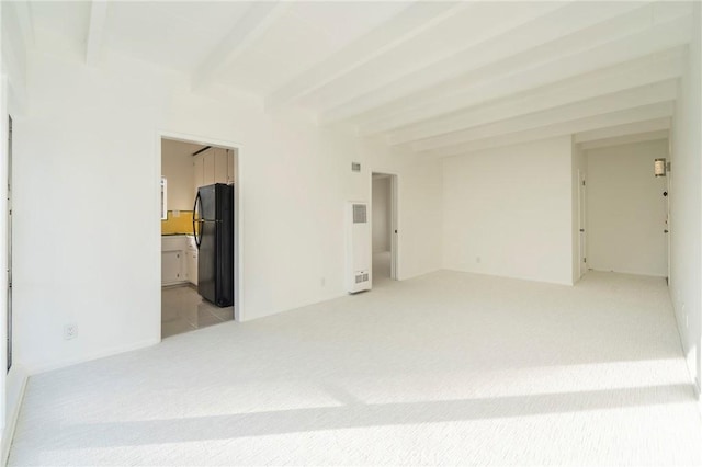 carpeted spare room featuring beamed ceiling