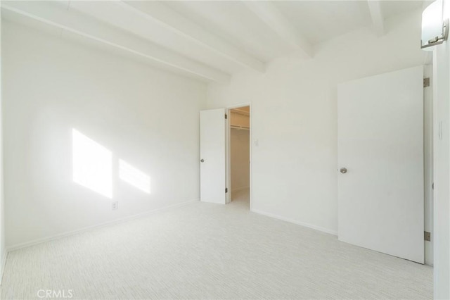 carpeted spare room featuring beamed ceiling