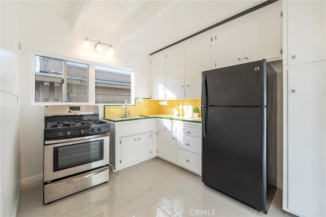 kitchen featuring white cabinetry, sink, backsplash, gas range, and black fridge