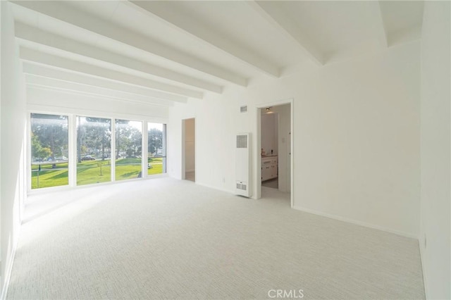 carpeted empty room featuring beamed ceiling