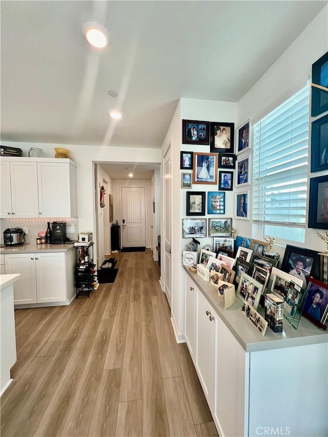 interior space featuring white cabinets, backsplash, and light hardwood / wood-style flooring