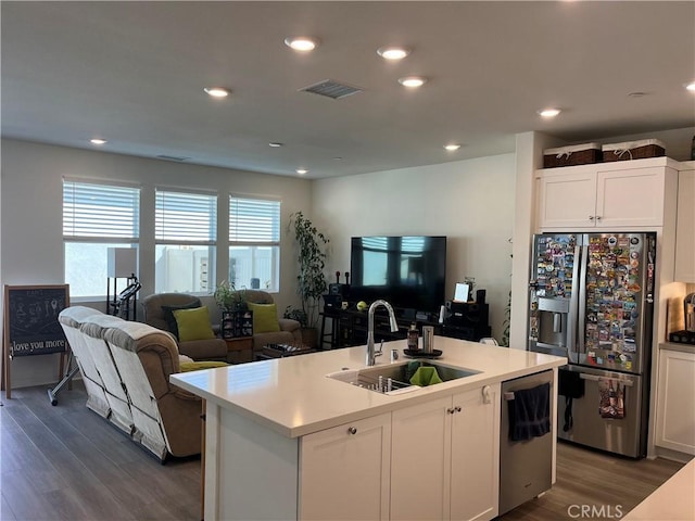 kitchen featuring dark wood-type flooring, sink, white cabinetry, stainless steel appliances, and a kitchen island with sink