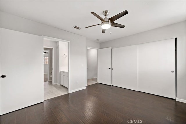 unfurnished bedroom with a closet, ensuite bath, dark hardwood / wood-style floors, and ceiling fan