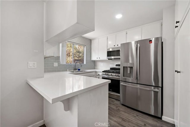 kitchen with sink, white cabinetry, stainless steel appliances, decorative backsplash, and kitchen peninsula