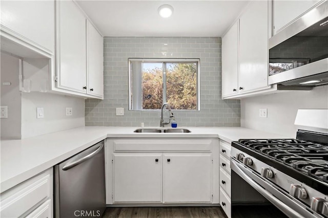 kitchen with appliances with stainless steel finishes, white cabinetry, sink, backsplash, and dark hardwood / wood-style flooring