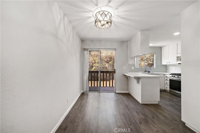 kitchen with white cabinets, a kitchen bar, dark hardwood / wood-style flooring, and stainless steel gas stove