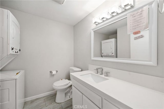 bathroom featuring toilet, vanity, and stacked washing maching and dryer