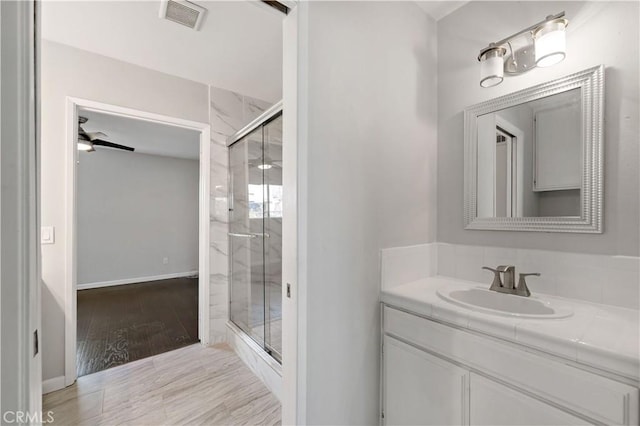 bathroom with a shower with door, vanity, wood-type flooring, and ceiling fan