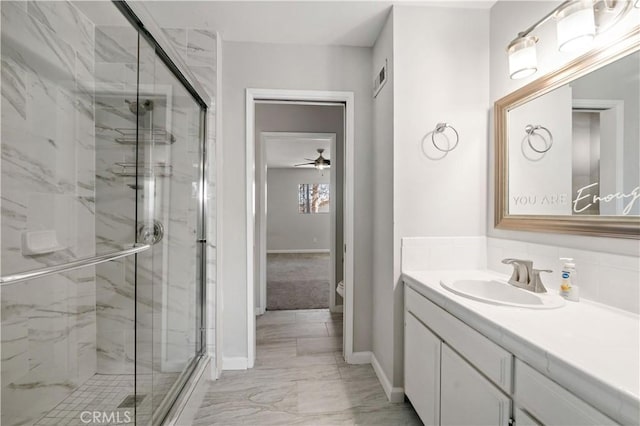 bathroom featuring a shower with door, vanity, and toilet