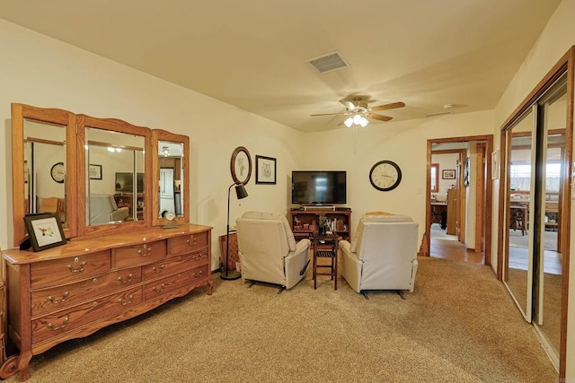 living area featuring visible vents, ceiling fan, and light carpet