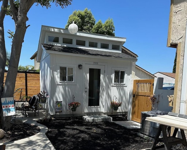 back of house featuring roof with shingles, a patio area, fence, and an outdoor structure