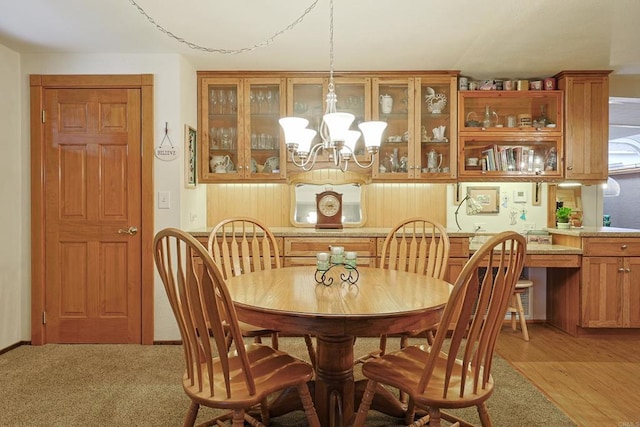 dining space with light wood-type flooring, light colored carpet, and an inviting chandelier