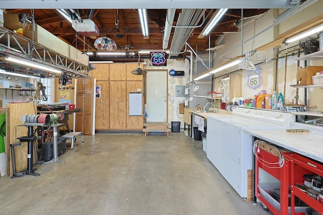 garage featuring a garage door opener, separate washer and dryer, and a workshop area