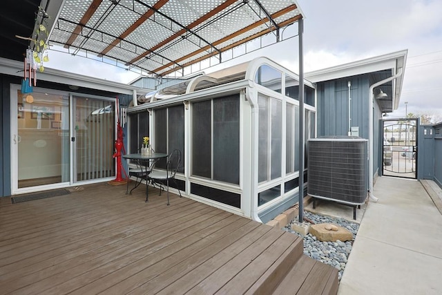 wooden deck with a sunroom, a pergola, and central AC unit