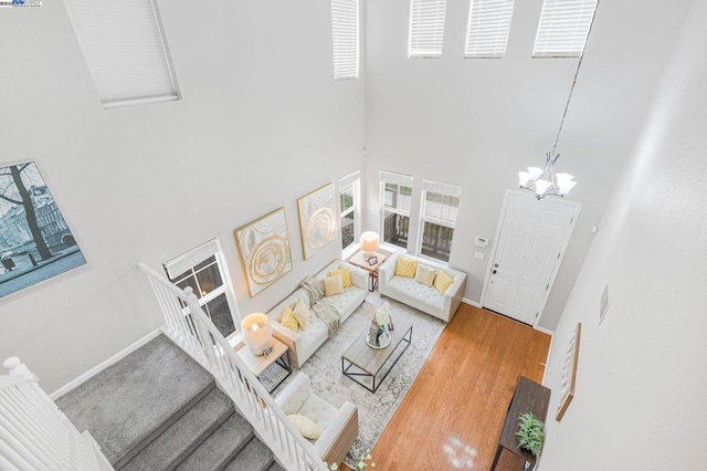 living room with wood-type flooring, a high ceiling, and a notable chandelier