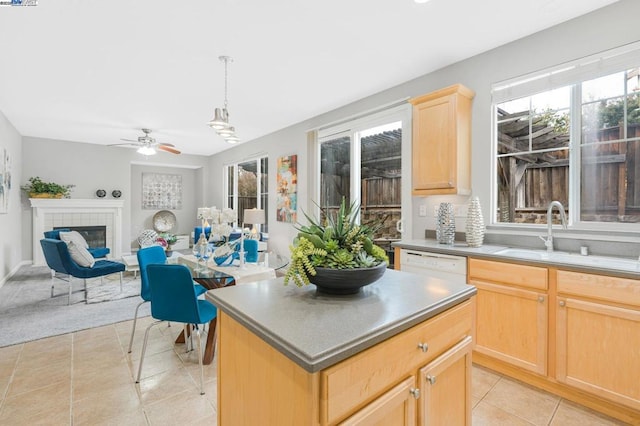 kitchen with pendant lighting, sink, a fireplace, a kitchen island, and light brown cabinetry