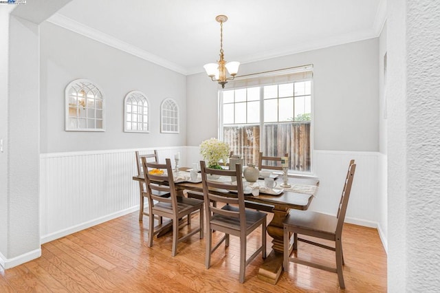 dining room with ornamental molding, a healthy amount of sunlight, an inviting chandelier, and light hardwood / wood-style flooring